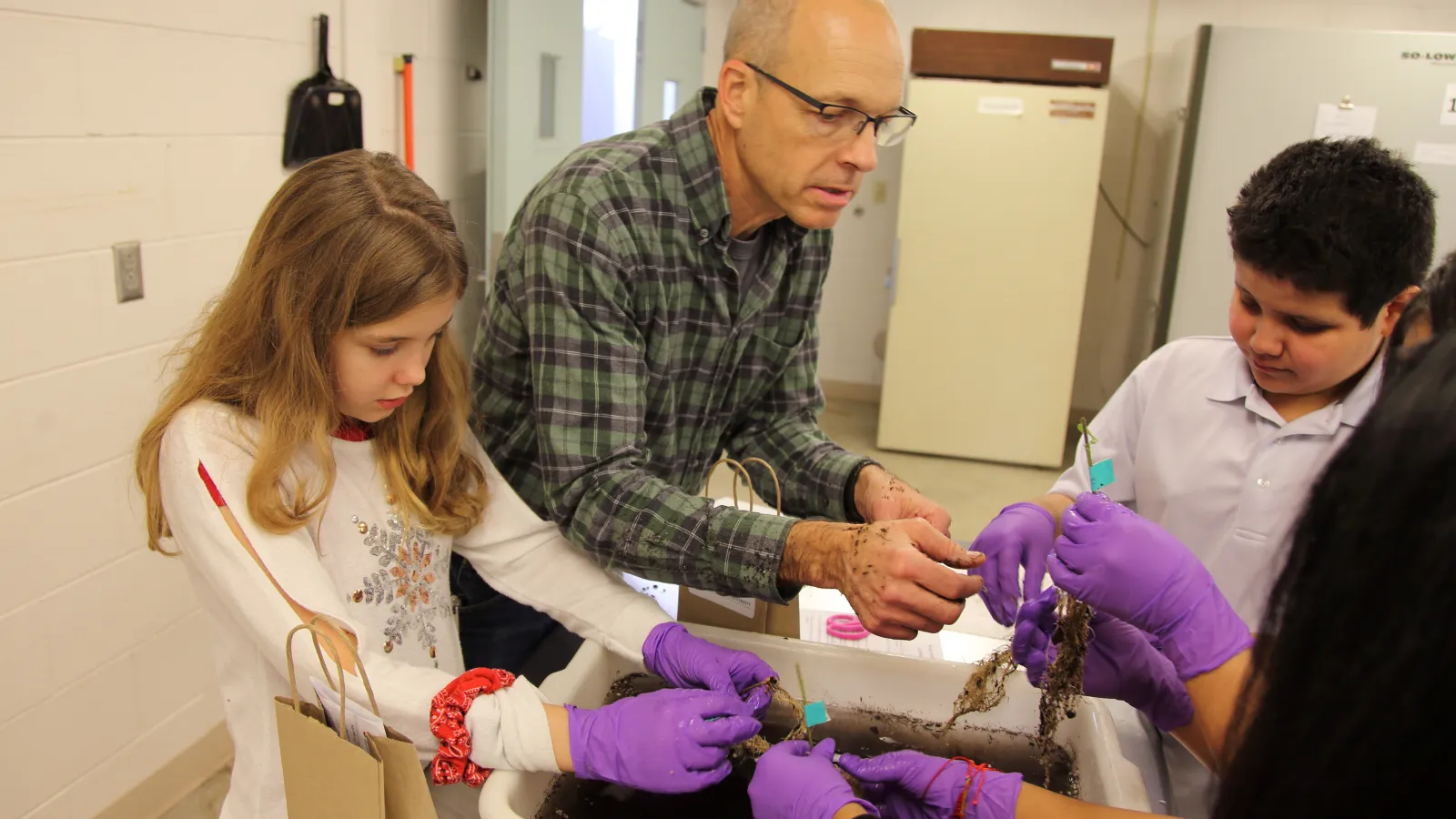 Professor and Children conducting a plant experiment 