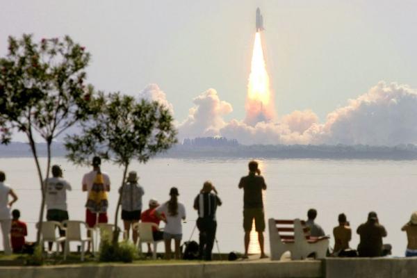 Space Shuttle Discovery lifts off from Kennedy Space Center as onlookers watch July 26, 2005, in Titusville, Florida. The shuttle crewmembers would have experienced time dilation and perceived the trip as taking less time than those on the ground. (Image credit: Mario Tama/Getty Images)